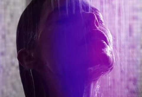 Lady taking a shower showing only her head with a neon violet background