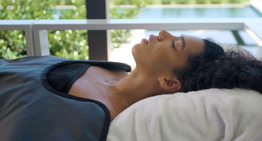 A woman relaxing on her back in a HigherDOSE Infrared Sauna Blanket