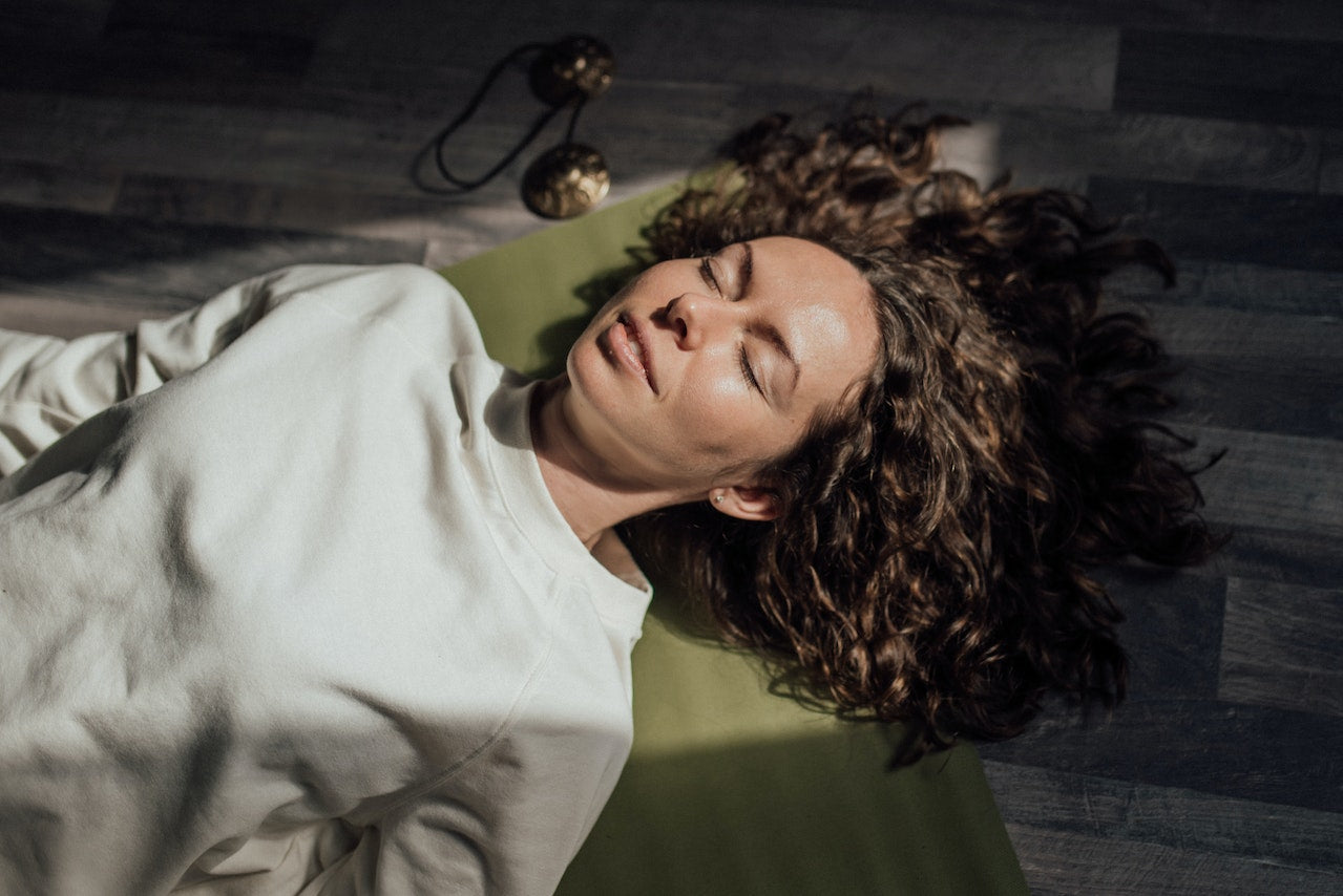 Woman with eyes closed while relaxing on a mat 