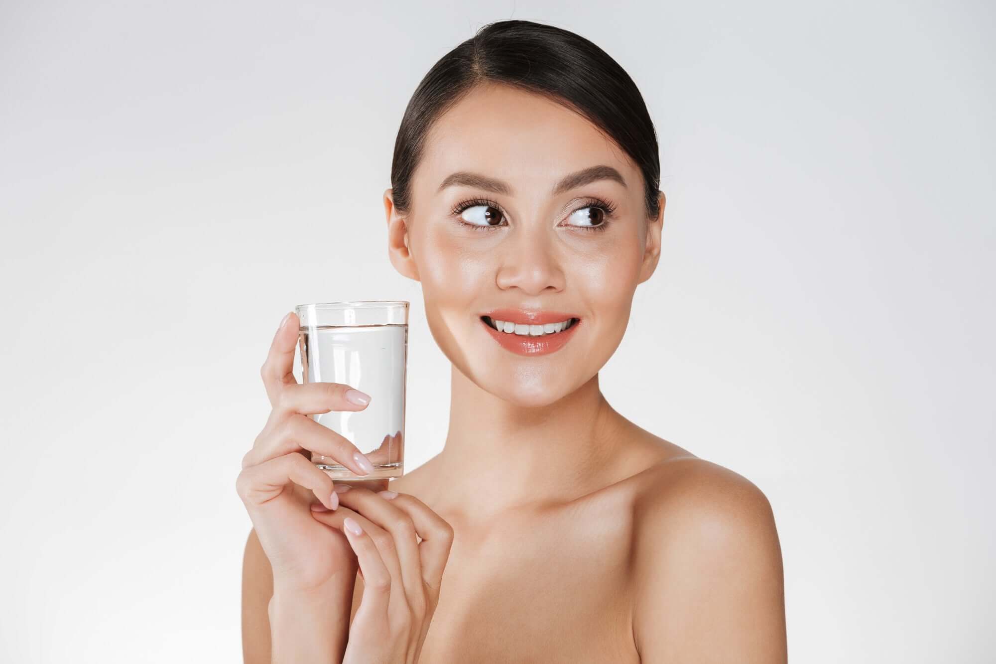 Woman who is naked down to shoulder level and is holding a clear glass with water