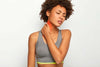 Woman wearing an exercise top and frowning and touching her neck