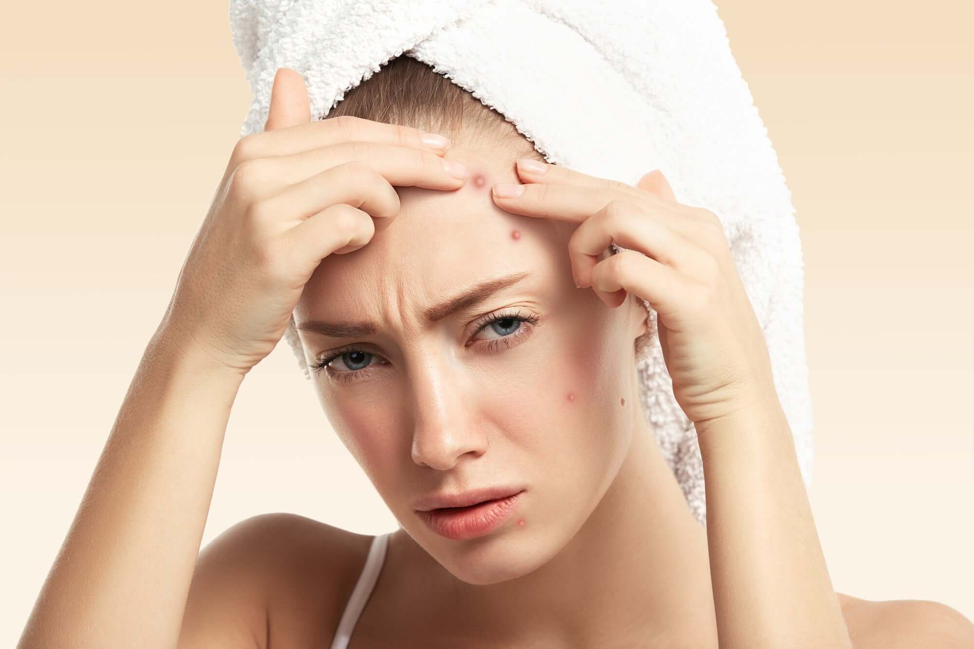 Woman checking out her acne while frowning