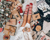 Headless person sitting on a rug amidst Christmas presents while holding a cup of tea with a lemon slice