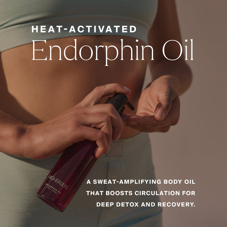 Person holding dark purple bottle of heat-activated endorphin oil against bare torso and shoulder.