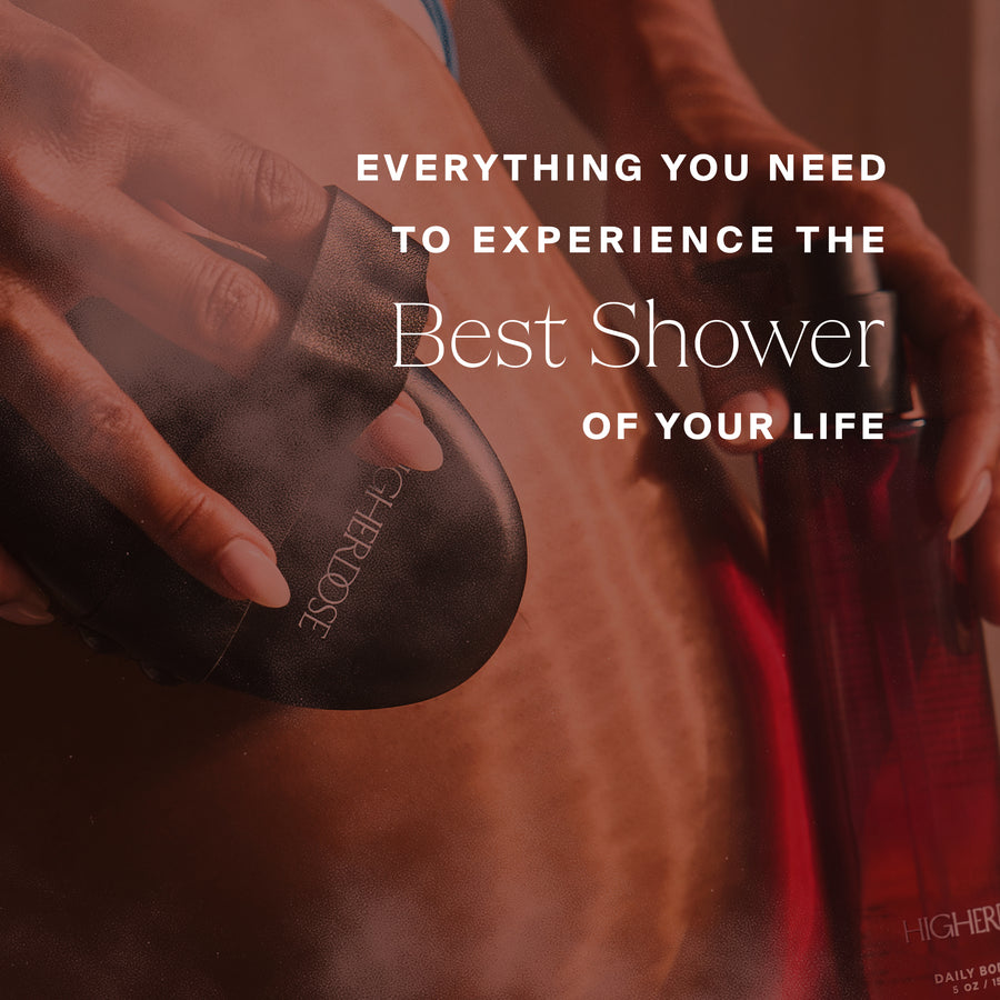 Hand holding a black spherical shower device with red light illumination on skin.