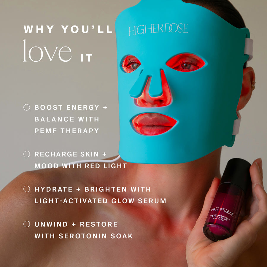 Turquoise silicone face mask with red facial features and hand holding purple bottle labeled Higher Dose serum.