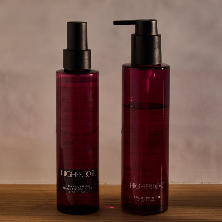 Two dark burgundy bottles with black spray and pump dispensers labeled 