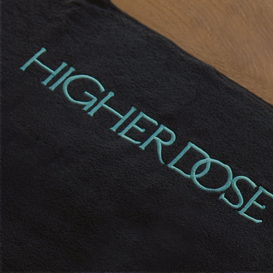 Black fabric with turquoise embroidered text reading 