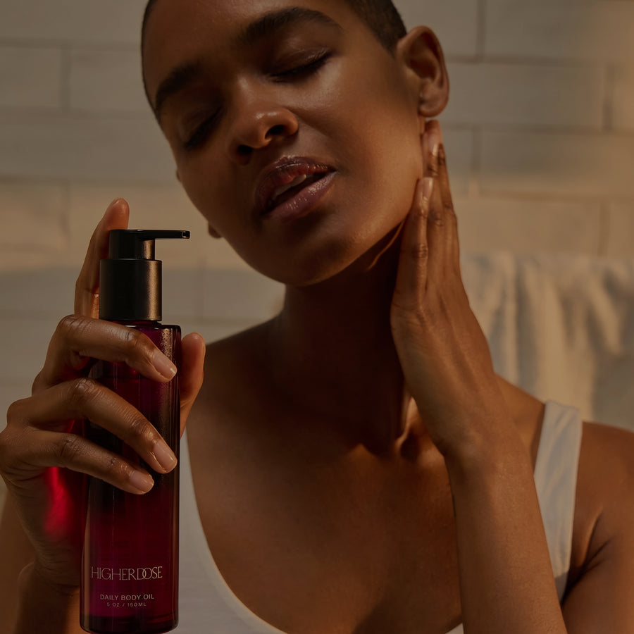Woman holding dark red pump bottle labeled 