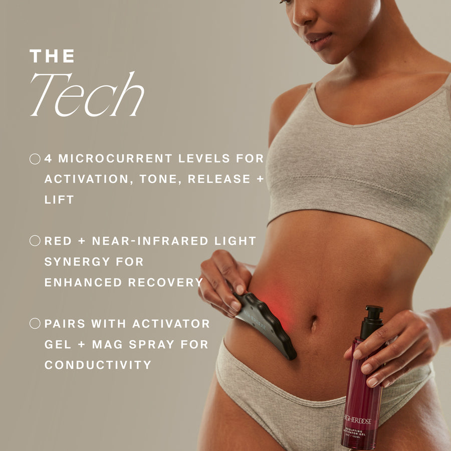 Person holding a black microcurrent device and red spray bottle against their torso, wearing beige crop top and shorts.