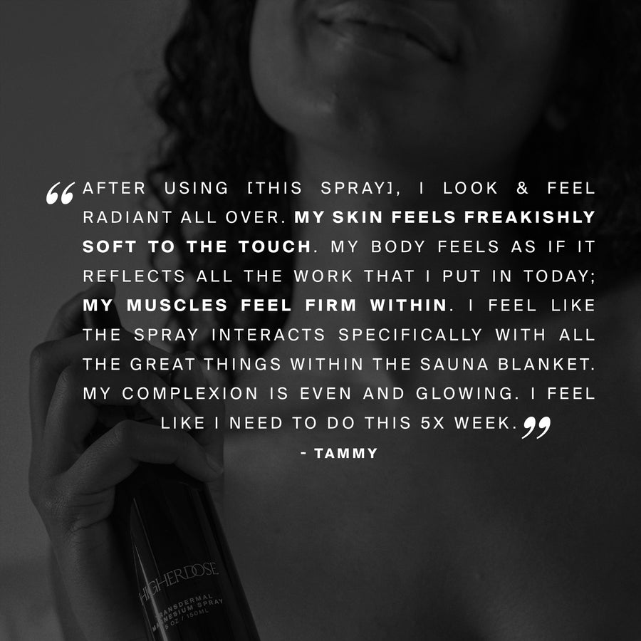 Black spray bottle with white label held in hand against neutral background.