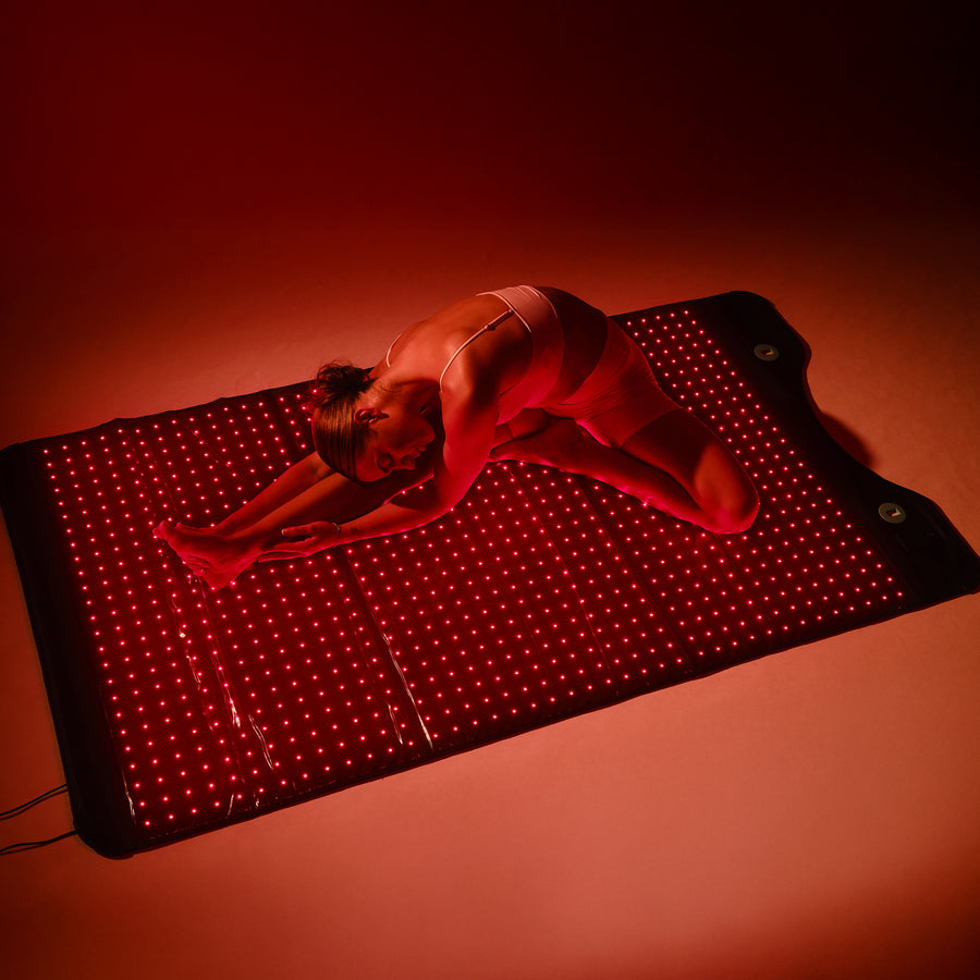 Red light therapy panel with grid of small LED lights and black border, shown against warm orange background.
