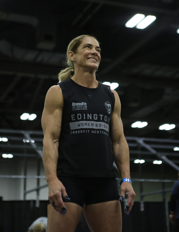 Woman wearing a black tank top with visible branding in an indoor setting