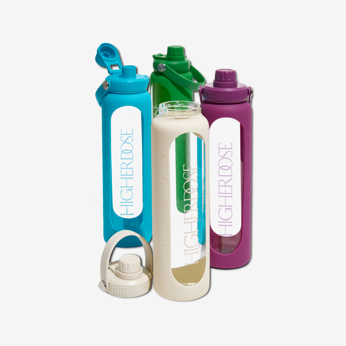 Three glass water bottles with time markers and colored silicone sleeves in turquoise, cream, and purple with matching lids a
