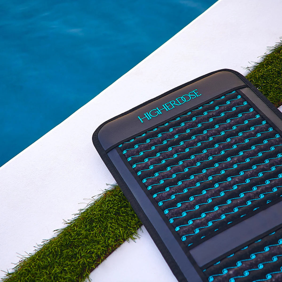 HigherDOSE Infrared PEMF Go Mat on poolside lounge area, symbolizing relaxation, recovery, and wellness on the go.