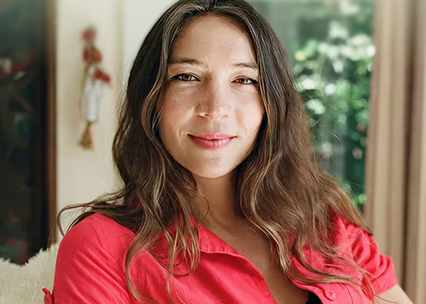 Brunette woman smiling sitting on a plush couch in a red shirt