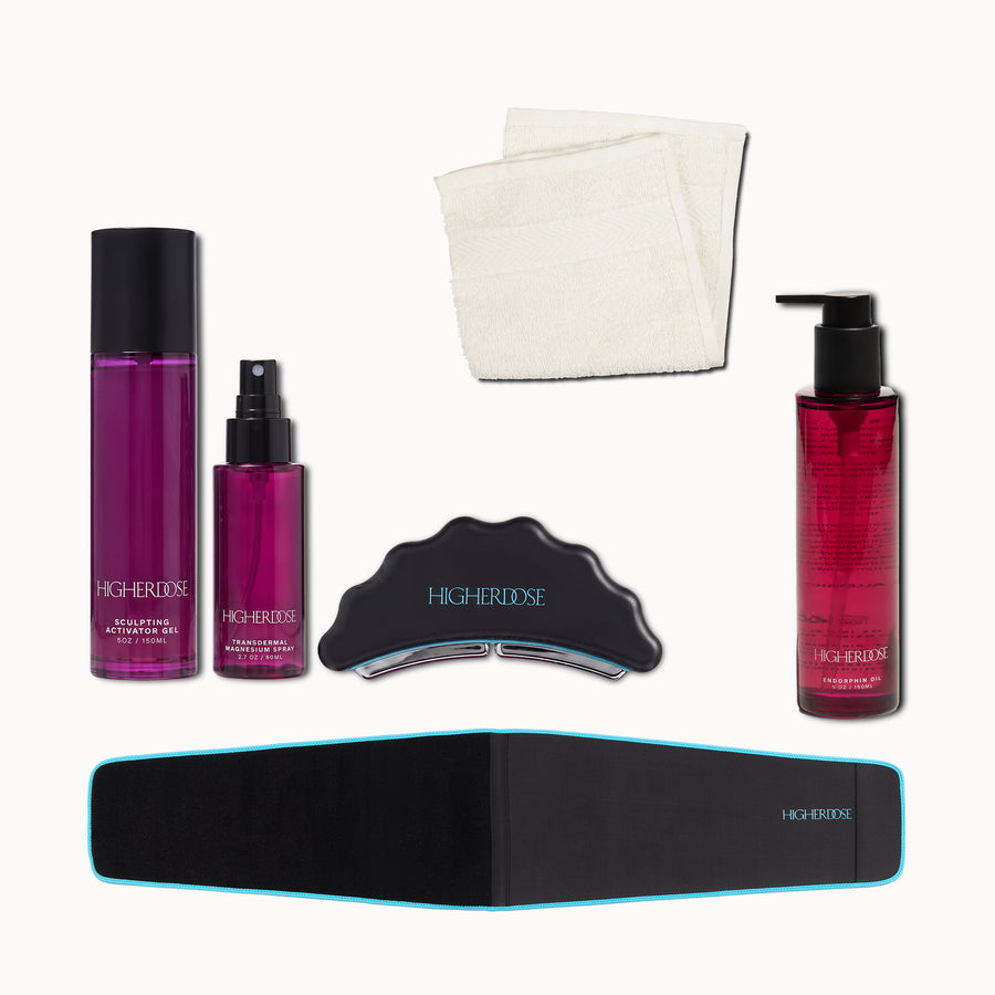 Five-piece kit containing two purple liquid bottles, one red pump bottle, black facial tool, black and blue waist belt, and c