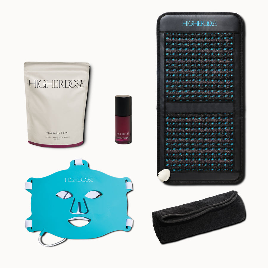 Four-piece Higherdose wellness bundle including cream pouch, burgundy serum, turquoise face mask, infrared mat pad, and black