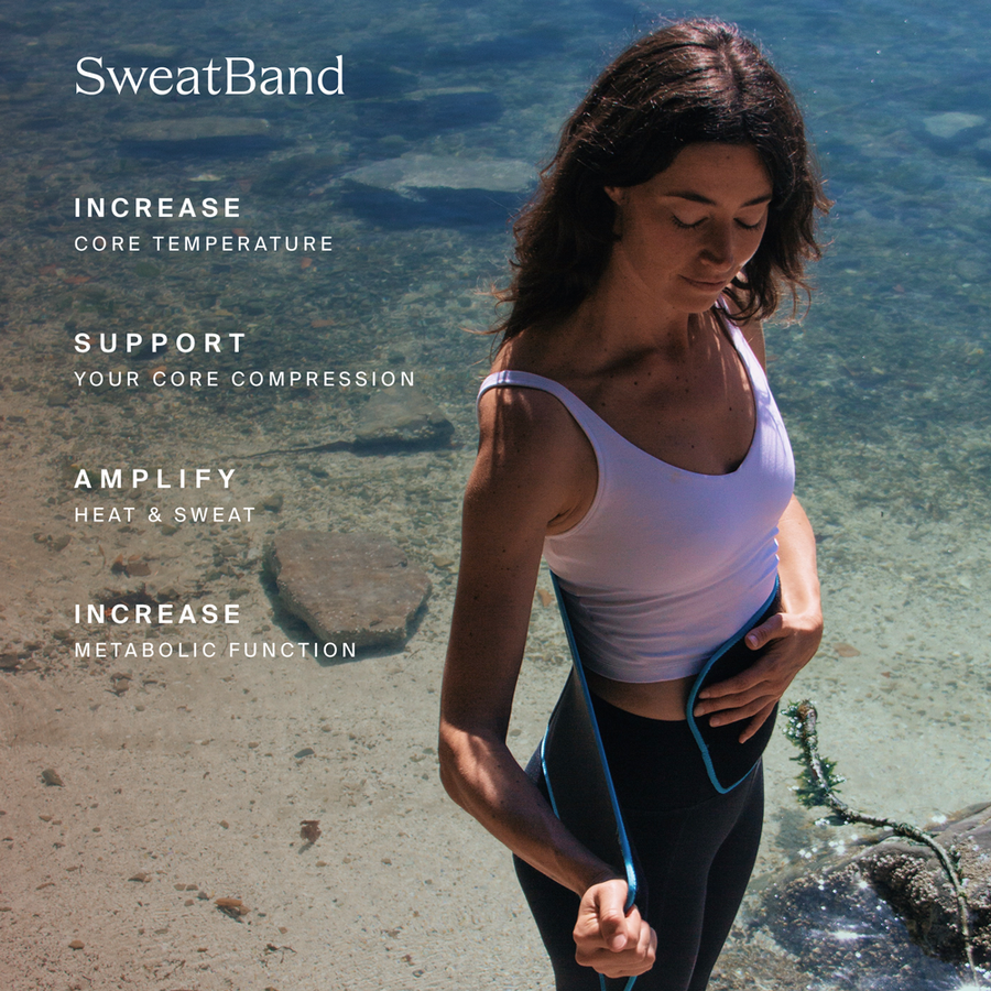 Woman wearing white tank top and black leggings with blue SweatBand around torso at beach.