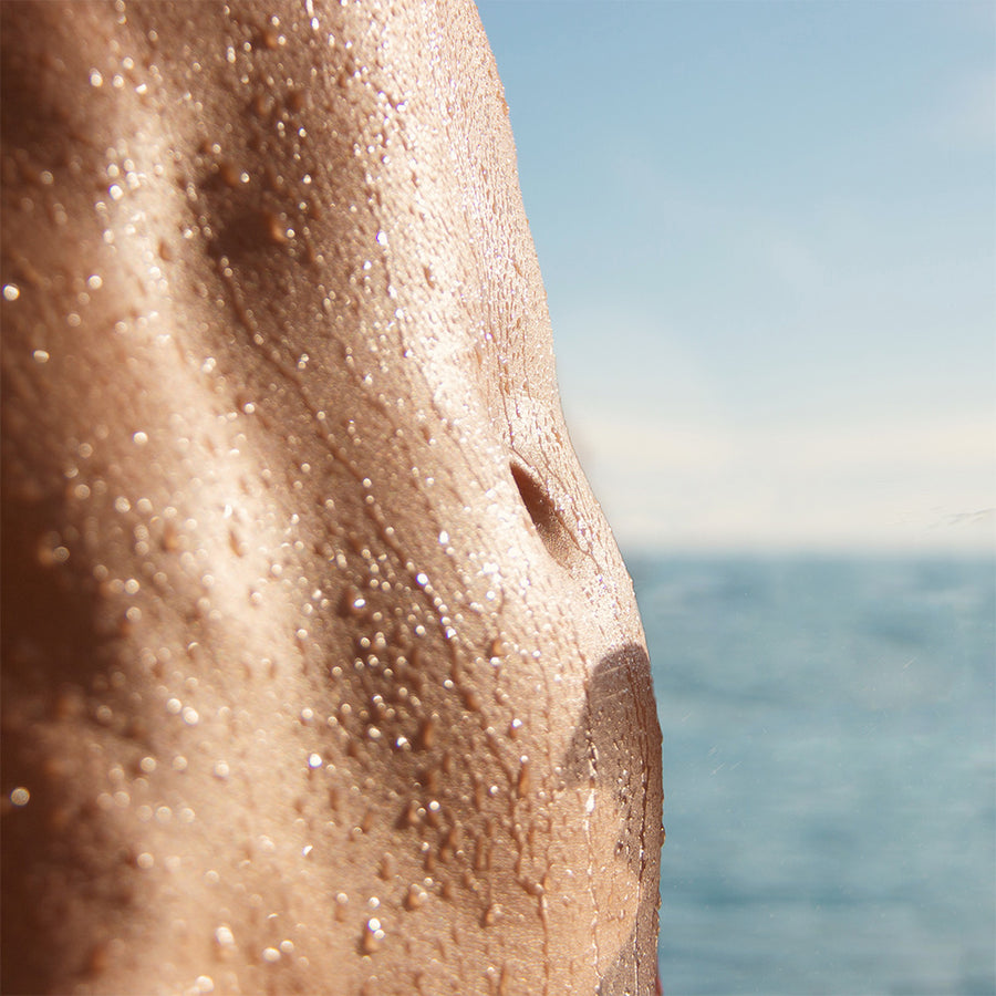 Tan sweatband worn on arm with moisture droplets, ocean and sky visible in background.