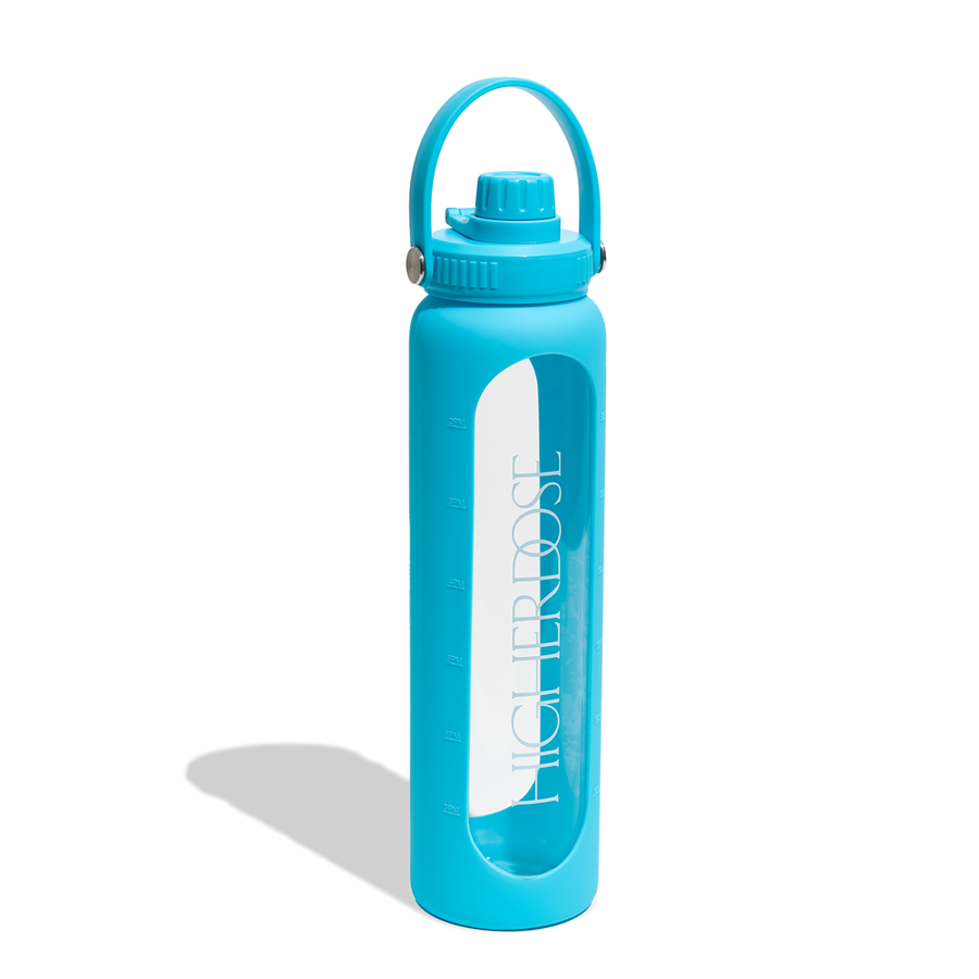 Turquoise water bottle with silicone sleeve, screw-top cap, carrying handle, and time markings visible on clear glass interio