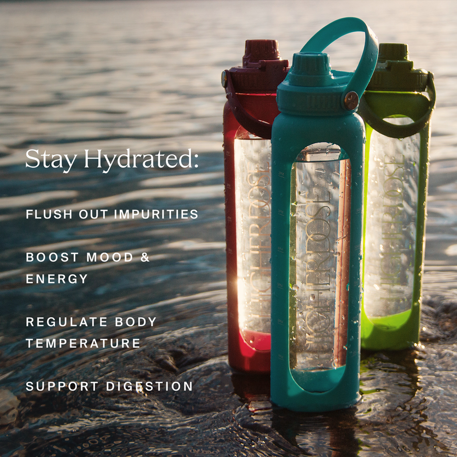Three glass water bottles with colored silicone sleeves and handles in teal, burgundy, and green displayed by water.