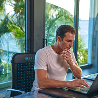 a man working in front of his laptop sitting on a higherdose go mat