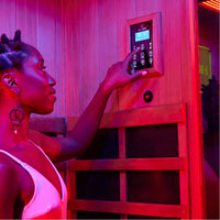 A woman using a control in a HigherDOSE infrared sauna box